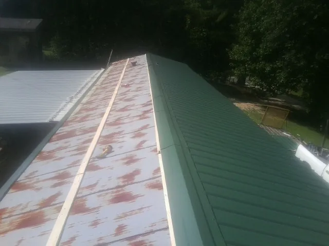 Old rusted panels beside newly installed green metal roofing — Wind Damage Roof Repair by Roofing Brothers in Rector