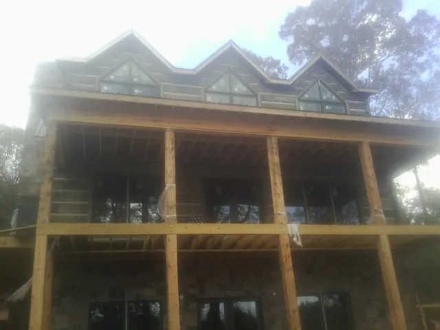 Dormers and porch framing on a large log home under construction — Roof Coating work by our crew in Rector