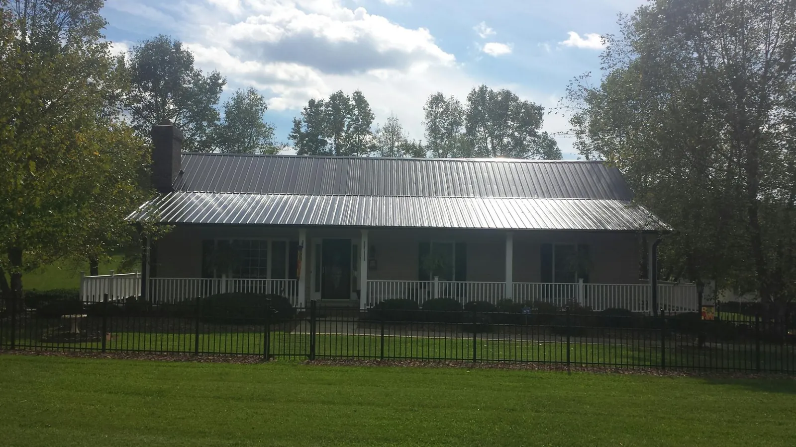 Gray metal roof on a brick ranch with a full width front porch — Gutter Guard Installation work by our crew in Rector