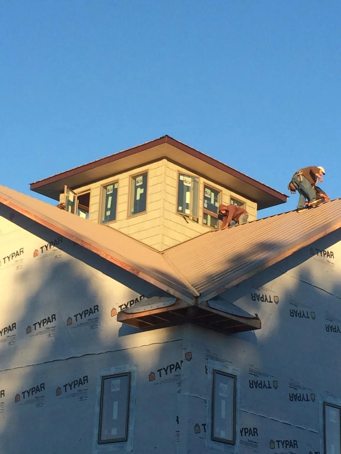 Roofers working around a rooftop cupola on a new metal roof at sunset — Roof Waterproofing in Rector by Roofing Brothers